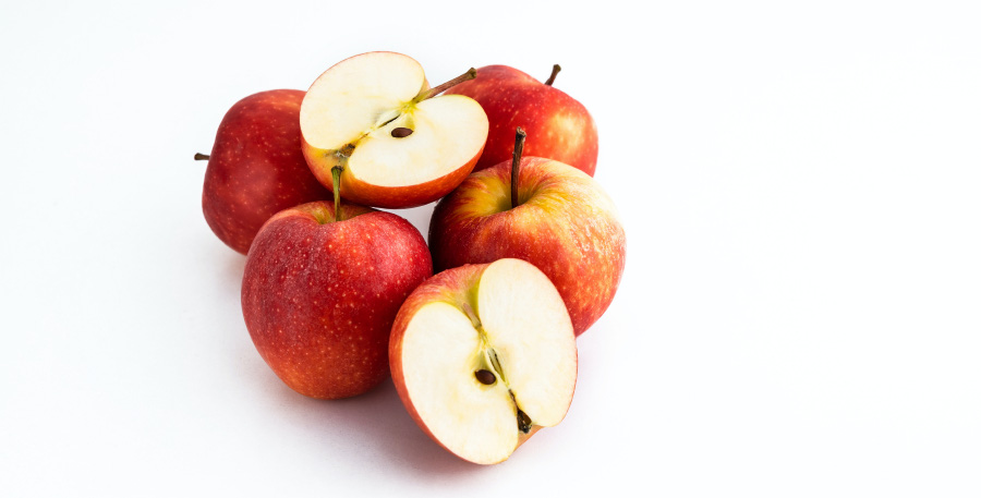 하얀 바닥 위에 사과를 4개와 1개를 반쪽으로 잘라서 속이 다 보이게 놓아둔 것 2개를 서로 포개어 놓아두고 찍은 사진