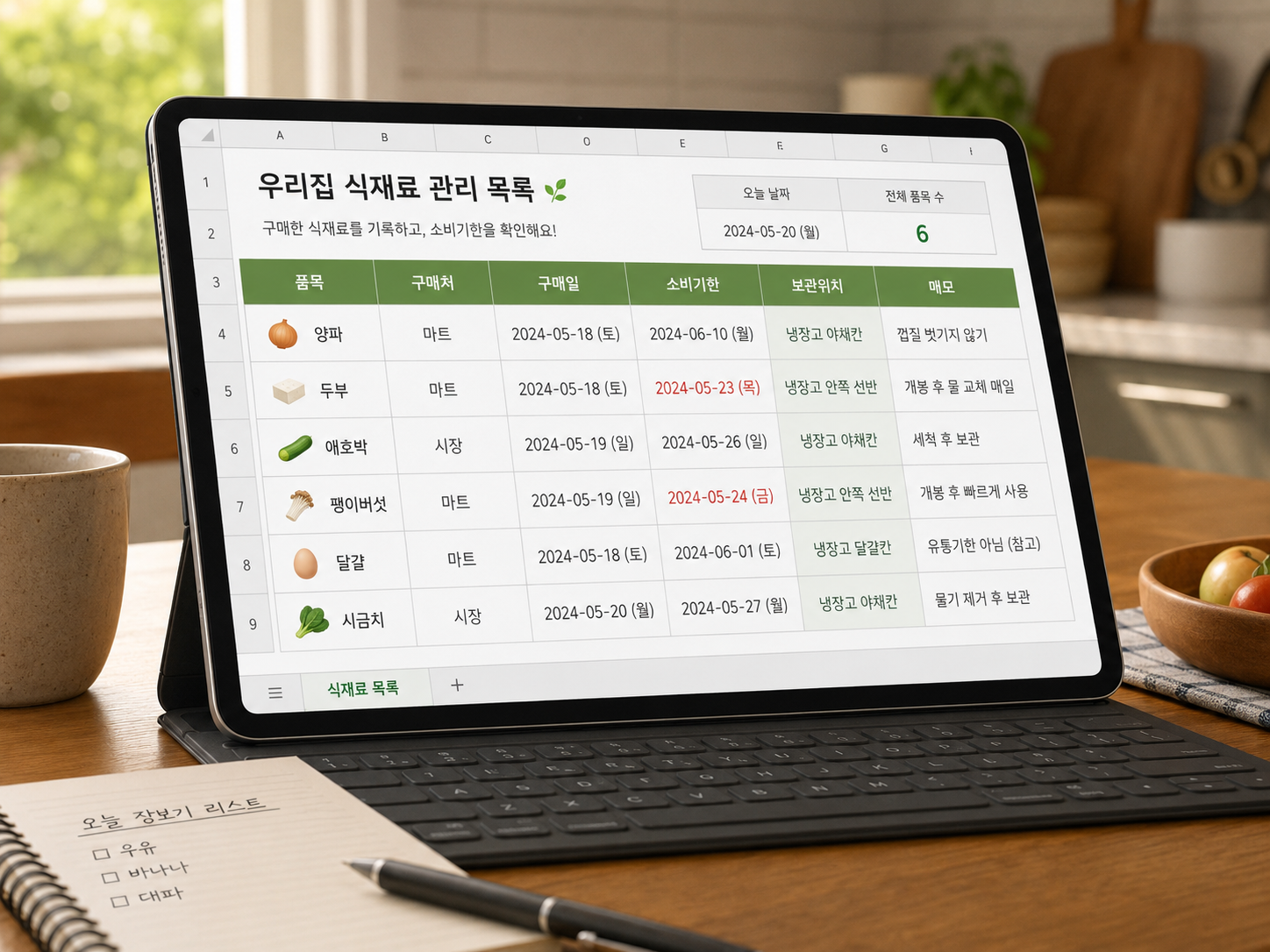 태블릿 PC 화면에 '우리집 식재료 관리 목록'이라는 제목의 스프레드시트가 띄워져 있고, 품목, 구매처, 구매일, 소비기한, 보관위치, 메모 항목이 깔끔하게 정리된 모습. 옆에는 '오늘 장보기 리스트'가 적힌 노트와 펜이 놓여 있다.