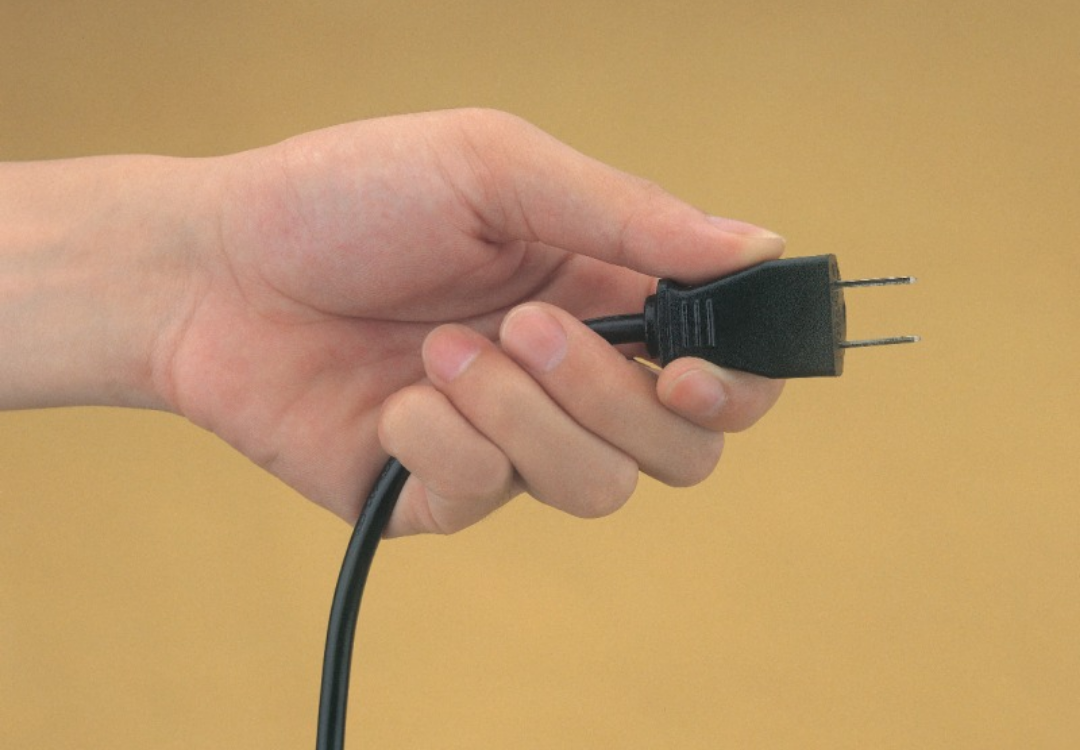 한 사람이 전선을 잡고 콘센트에 꽂고 있다.