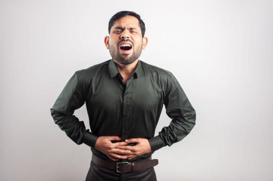 한 남성이 자기 배를 움켜 쥐고 괴로워 하고 있다.