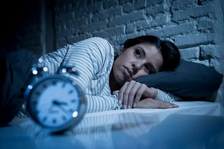 한-여성이-불이-꺼진-방의-침대-위에서-불면증으로-잠들지-못하고-눈을-뜨고-있다