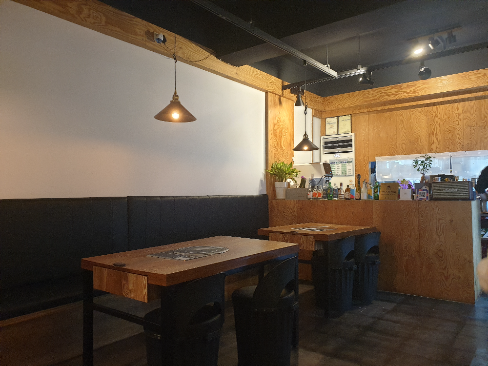 흰 벽면과 우드 테이블 그리고 회색 바닥, 은은한 조명이 세련된 느낌을 준다.