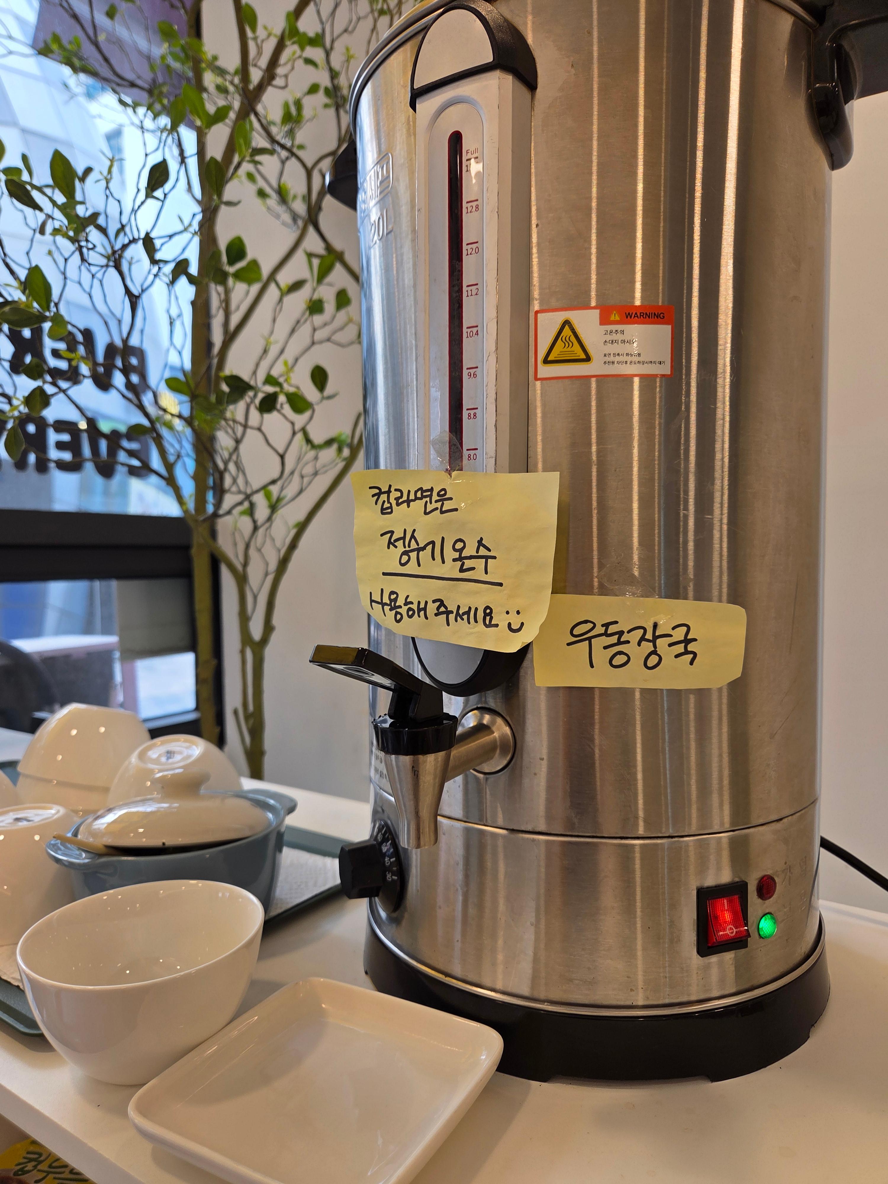 키토키토 매장 셀프 코너에 준비된 우동 장국 온수기와 깔끔하게 정리된 그릇들