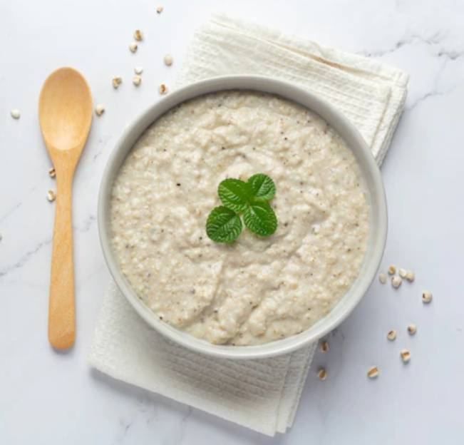 하얀색 그릇에 죽이 담겨 있고, 위에 네잎클로버가 올려져있다.