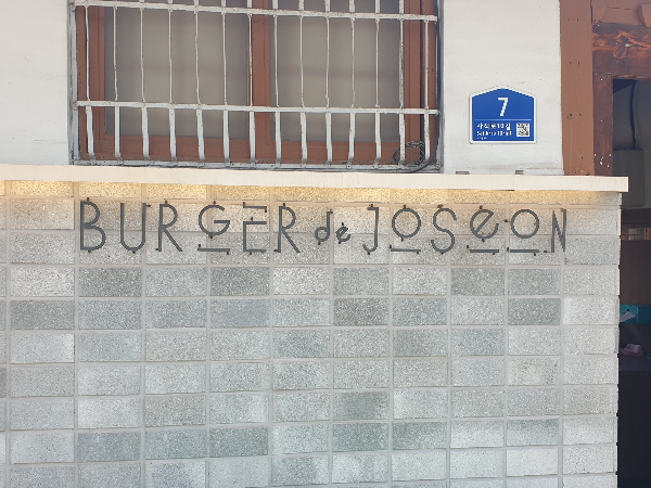 한옥 벽앞에 벽돌을 쌓아 담으로 만들고 거기에 간판을 달았다.