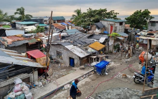 다 낡고 부서진 지붕들과 지저분해 보이는 거리, 발전기를 돌려야 하는 사람이 발전기를 들고 움직이는 모습이 담긴 필리핀 빈민가 바세코