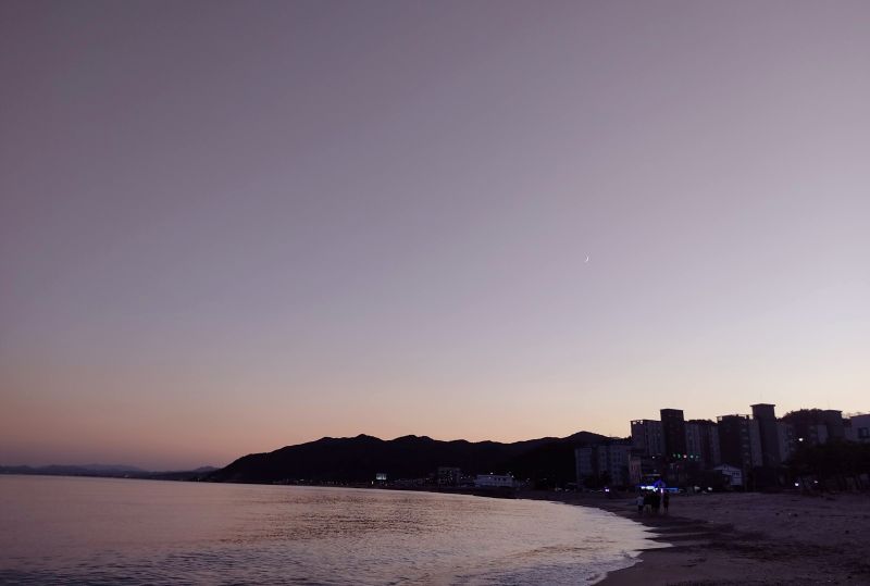 하늘과 같은 주황색이 된 바다와 어두워진 하늘 사이로 보이는 초승달