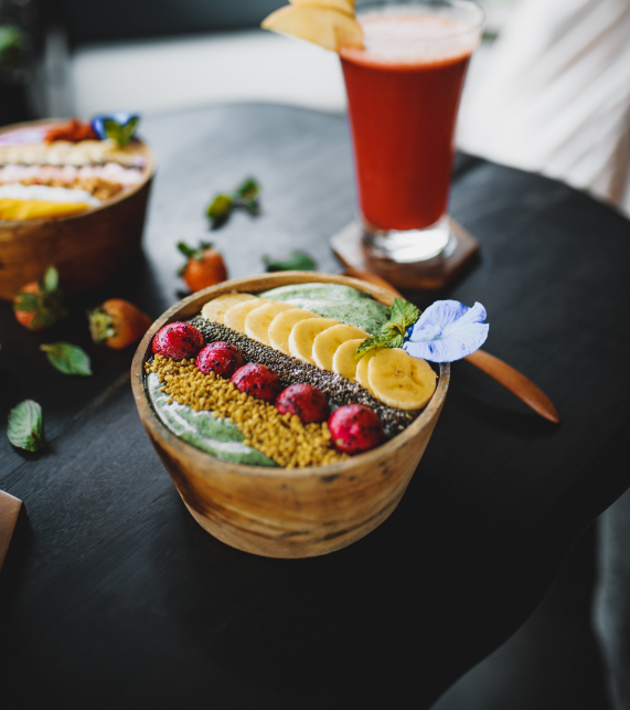 바나나 들어있는 스무디볼과 주스잔이 식탁위에 놓여 있는 사진