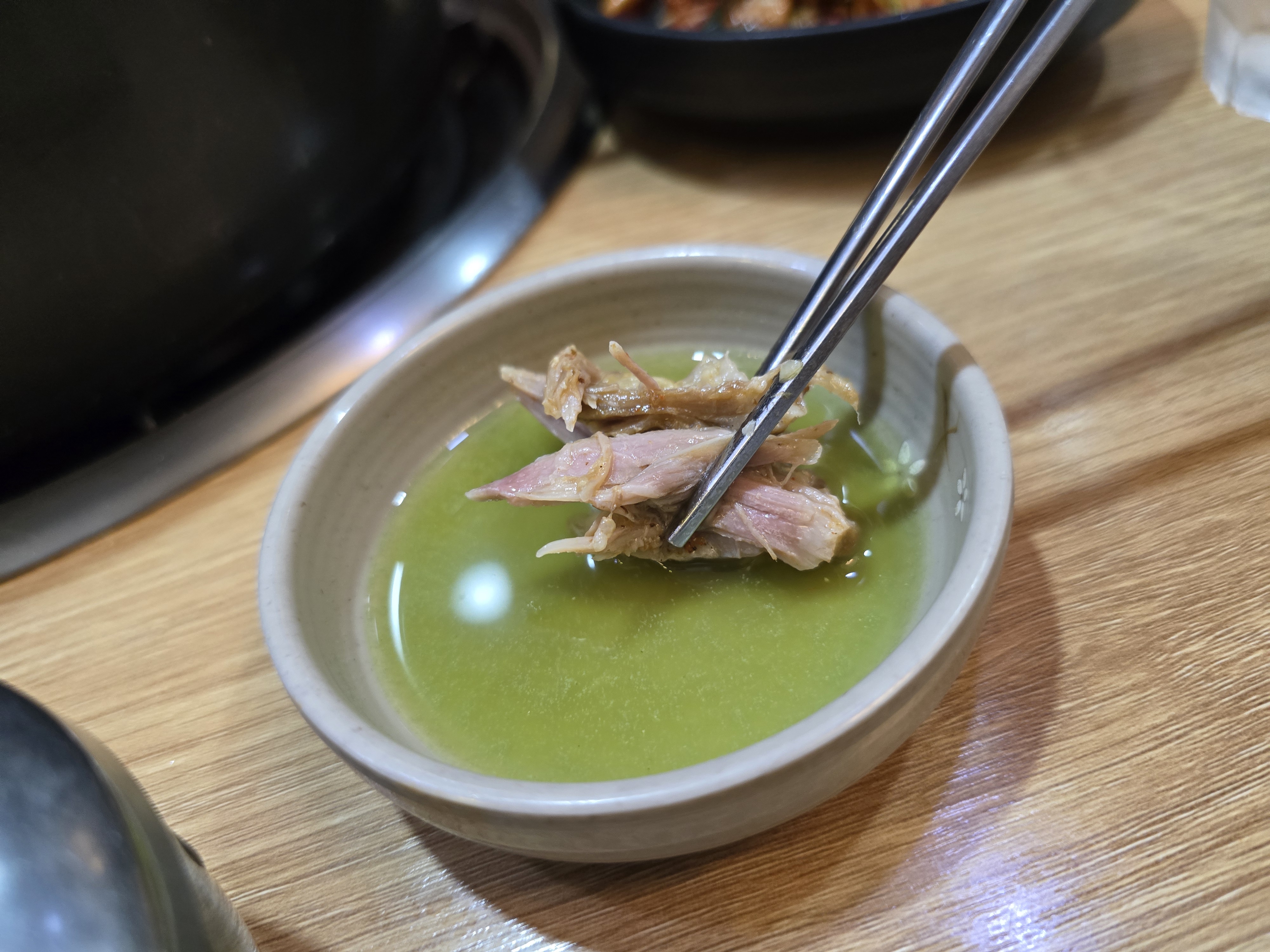 감자탕 살코기를 소스에 찍는 모습