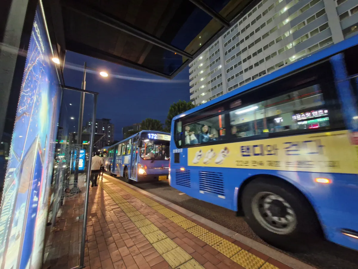 버스정류장에-파란색-버스들이-지나치고-있는-모습