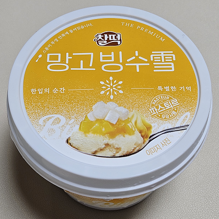찰떡 망고 빙수 설 포장사진. 노란색 바탕에 숟가락으로 빙수를 한 스푼 가득 뜬 사진이 있다.