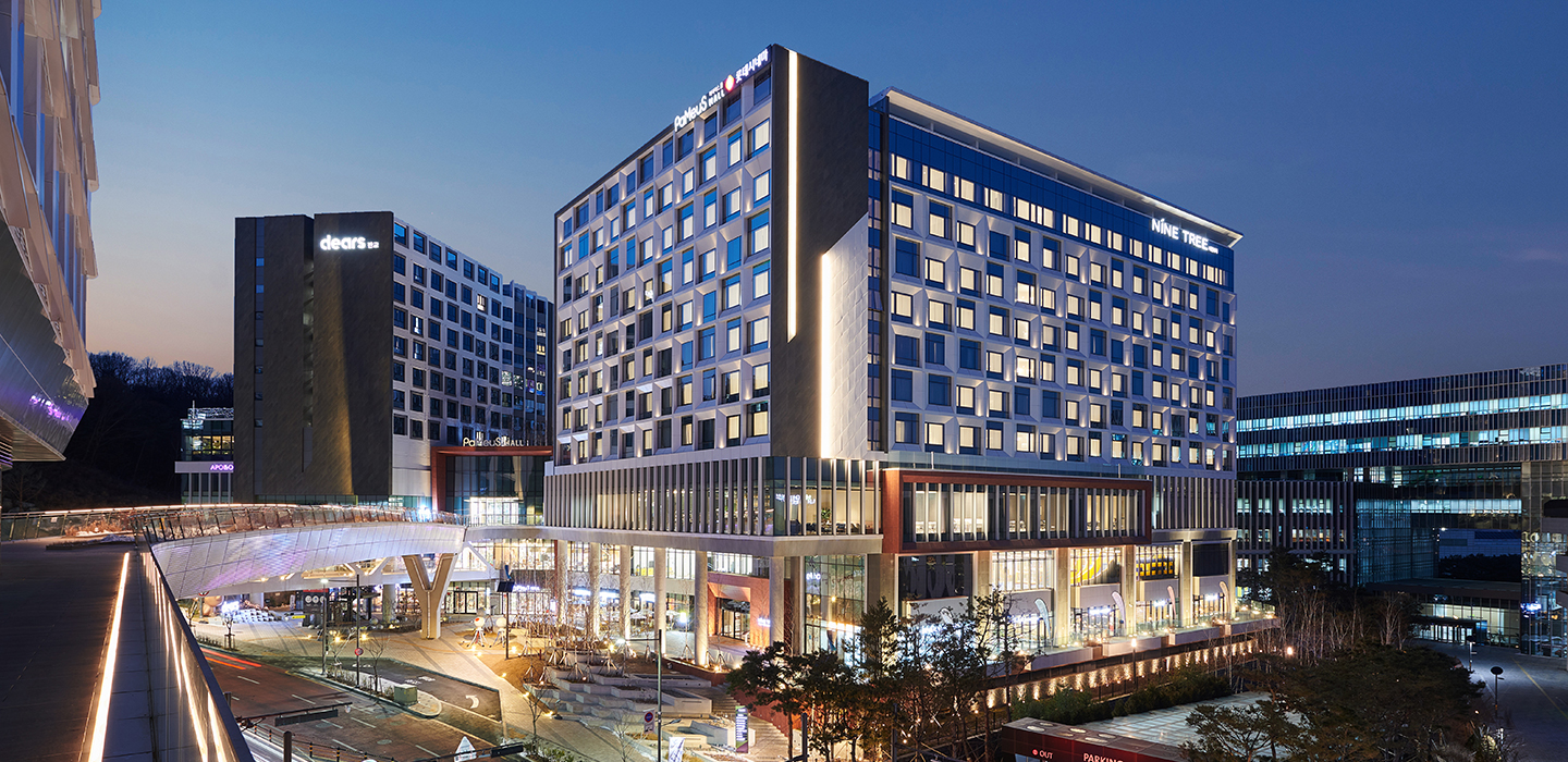 경기도 성남시 분당구에 위치한 나인트리 프리미어 호텔 서울 판교 외관. 야경 속에서 화려하게 조명을 밝힌 건물과 주변 상업시설이 세련된 도심 분위기를 자아낸다.