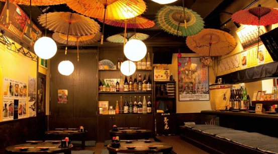 일본식 식당의 홀 내부 사진 천장에는 일본식 우산이 있고 그 밑에 노란색을 띄는 원형의 조명들이 있다.