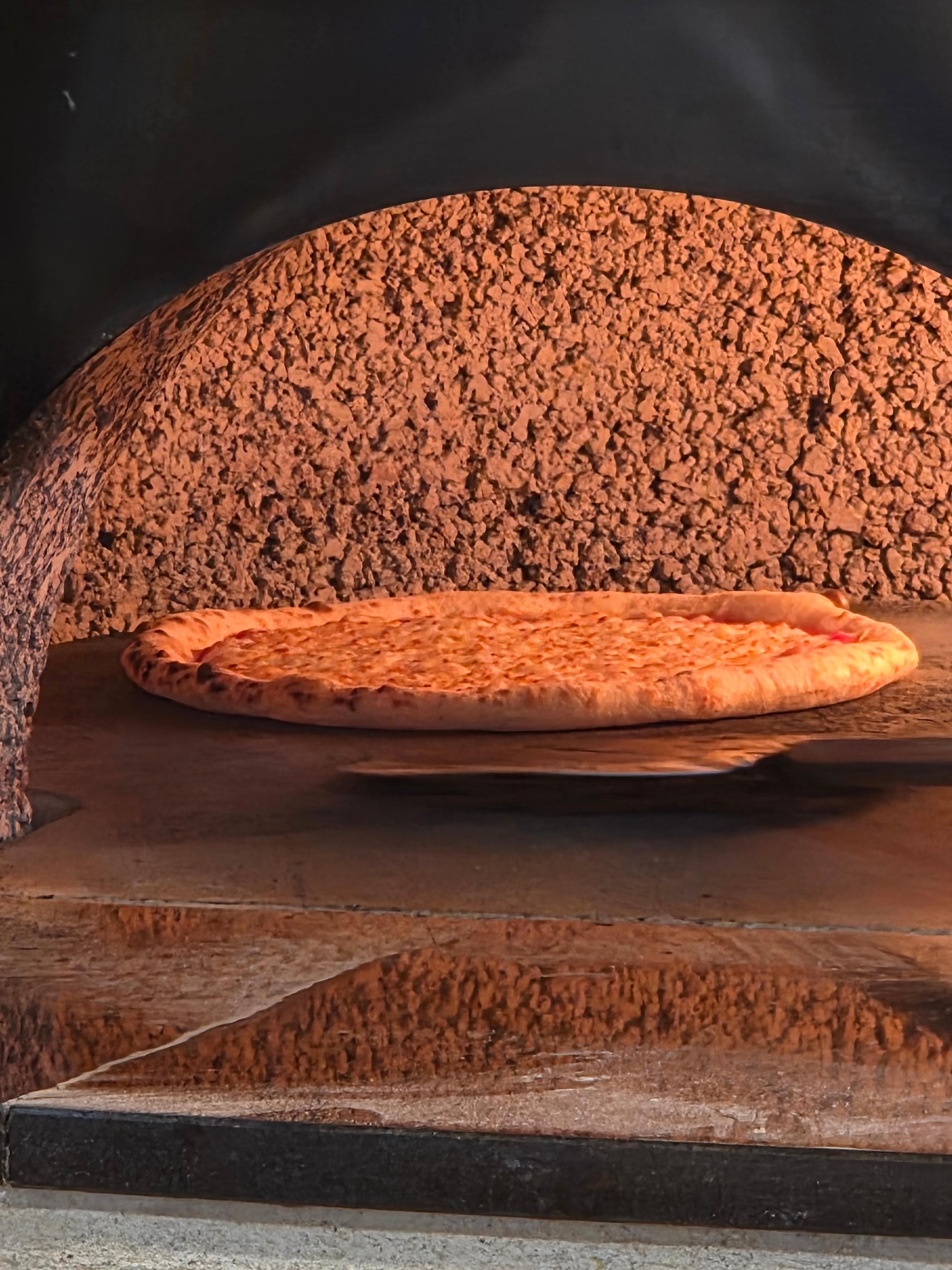 화덕 안에서 노릇하게 구워지고 있는 피자 도우 클로즈업