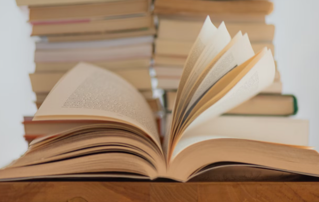 쌓여있는 책들과 펼쳐져 있는 책 사진