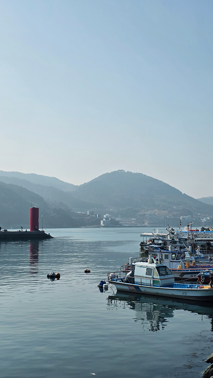 등대가 보이는 바닷가에 정박해 있는 배