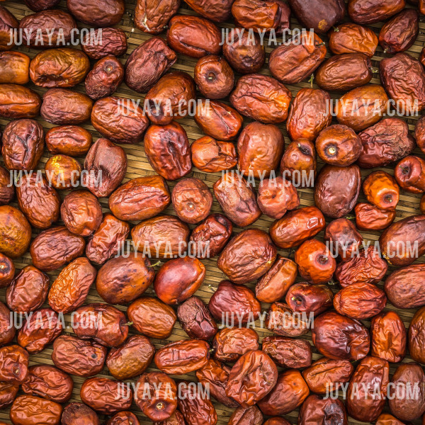 다양한 크기와 색상을 가진 말린 대추가 바닥에 넓게 펼쳐져 있는 모습. 자연 건조된 건강 간식.