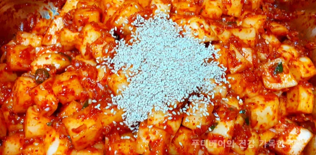 양념에-버무린-깍두기에-깨를-넣는-모습