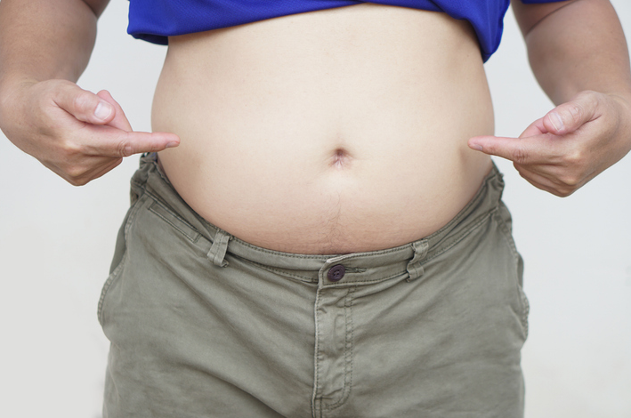 마른 체형의 남성이 배만 살이 찐 배를 손으로 가리키는 모습