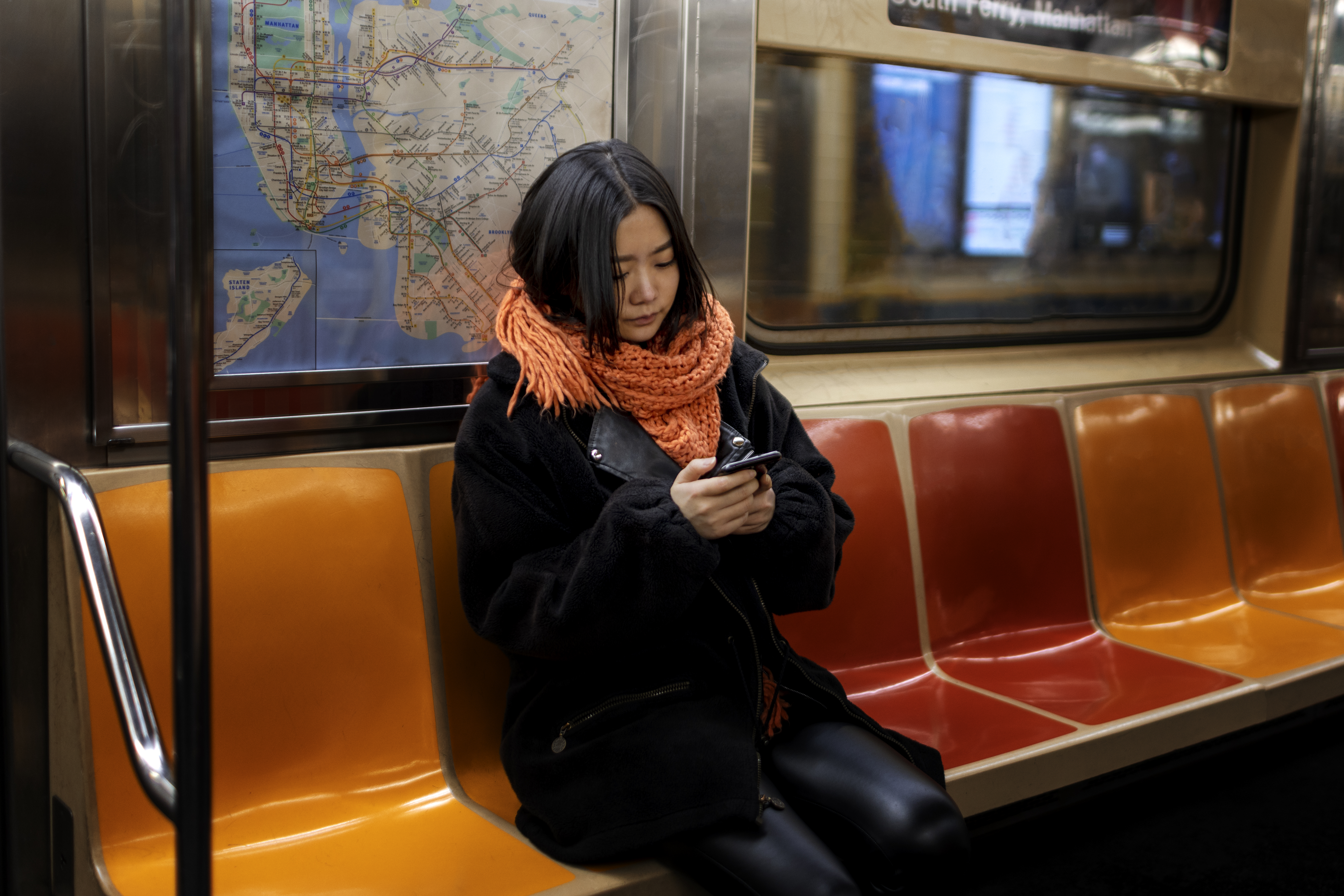 지하철 안에서 조용히 앉아 핸드폰을 보는 Z세대 여성