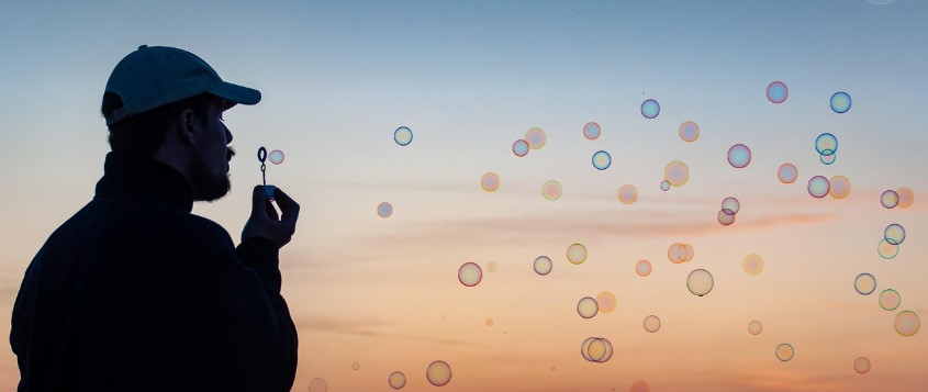 중년의 남성이 석양무렵에 비누방울을 불고 있는 실루엣