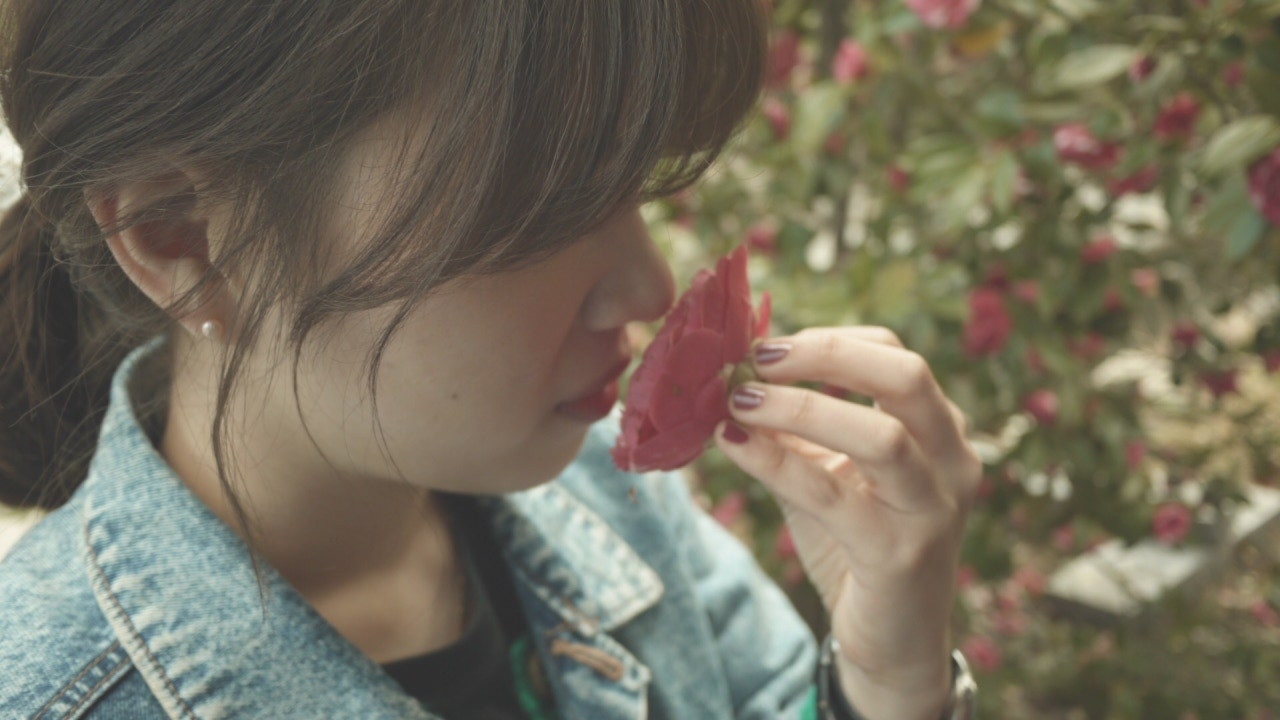 여자가 동백꽃 향기를 맡고 있는 사진