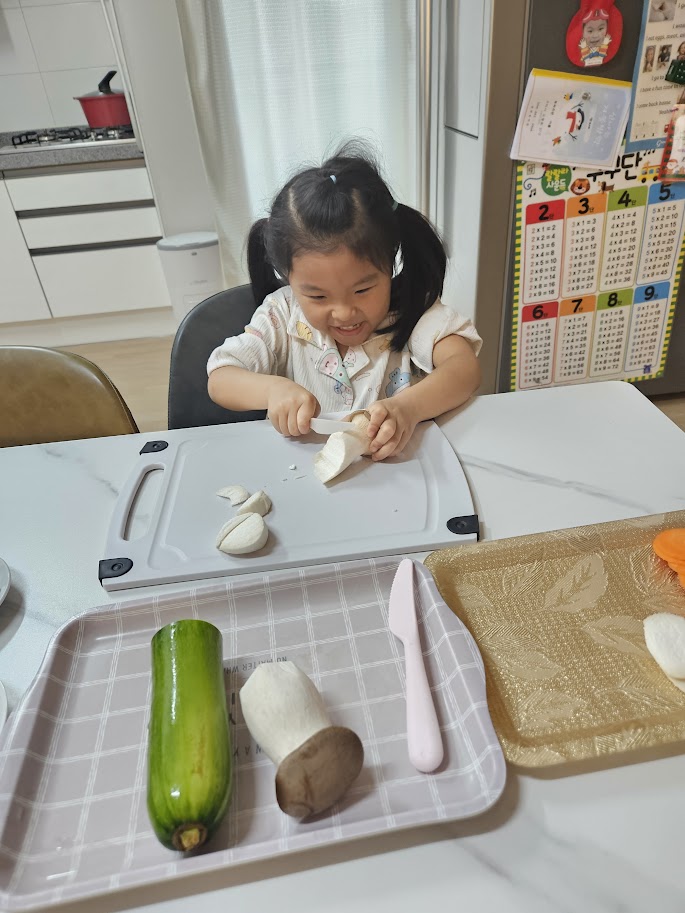 수확한 버섯을 플라스틱 칼로 직접 손질하며 요리를 돕는 초등학교 1학년 아이