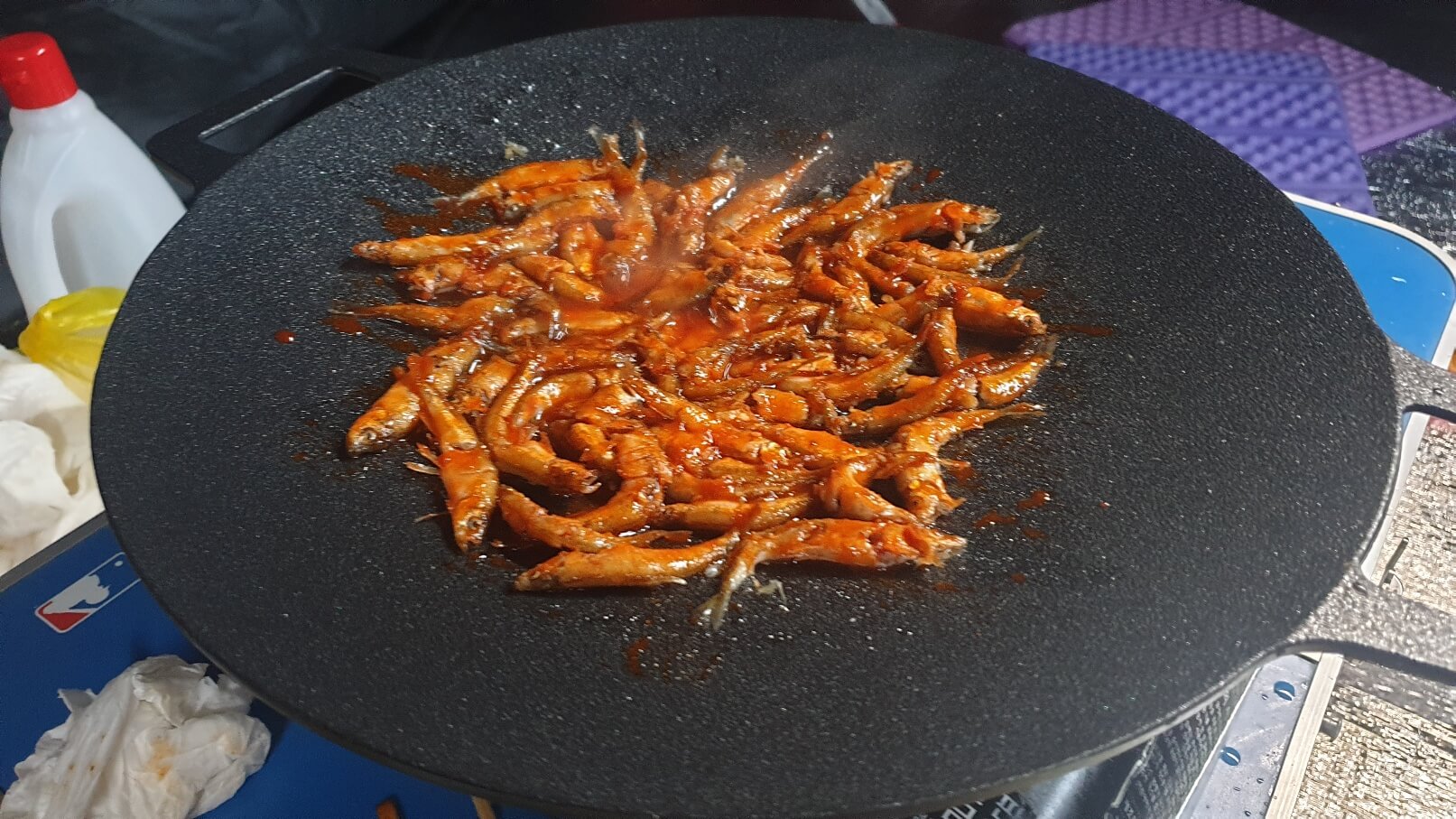 빙어에 빨간양념을 발라 불판에서 구워지고 있는 이미지