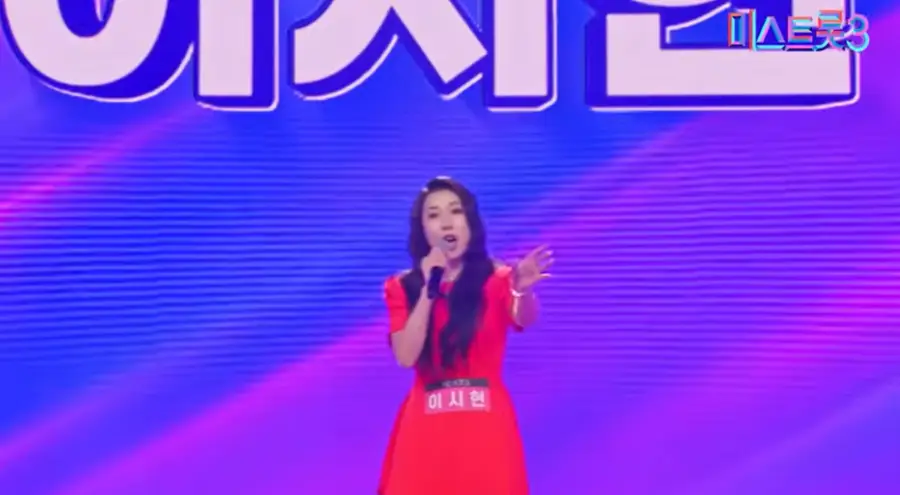미스트롯3- 불은색 반팔 원피스를 입고 오른손으로 마이크를 든채 관중을 바라보고 노래하는 이시현 출연자