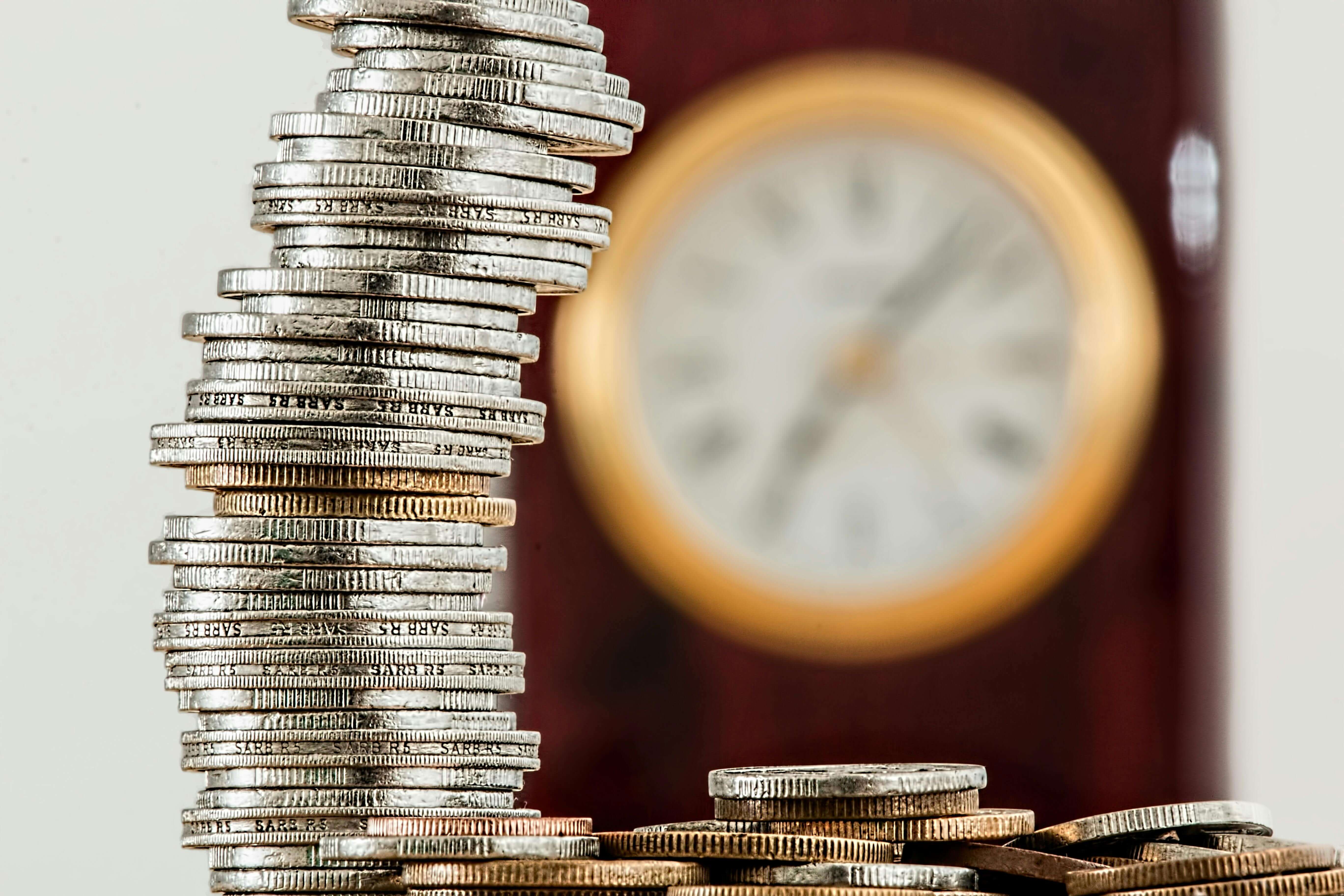 coins piled up and a clock in the background. 썸네일