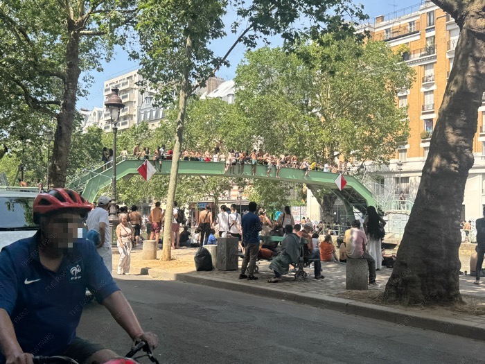 People gathering on a bridge and diving into Canal Saint-Martin during a severe heatwave in Paris