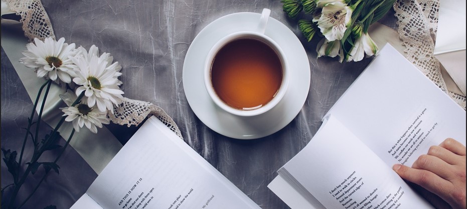 작은 국화꽃송이와 커피가 놓여있는 탁자에 앉아 독서를 하고 있는 듯한 사진