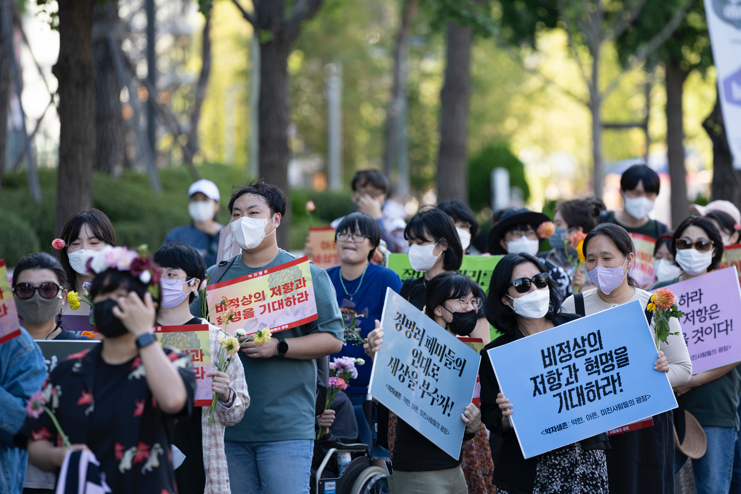 시민들이 피켓과 꽃을 들고 행진하고 있다.
