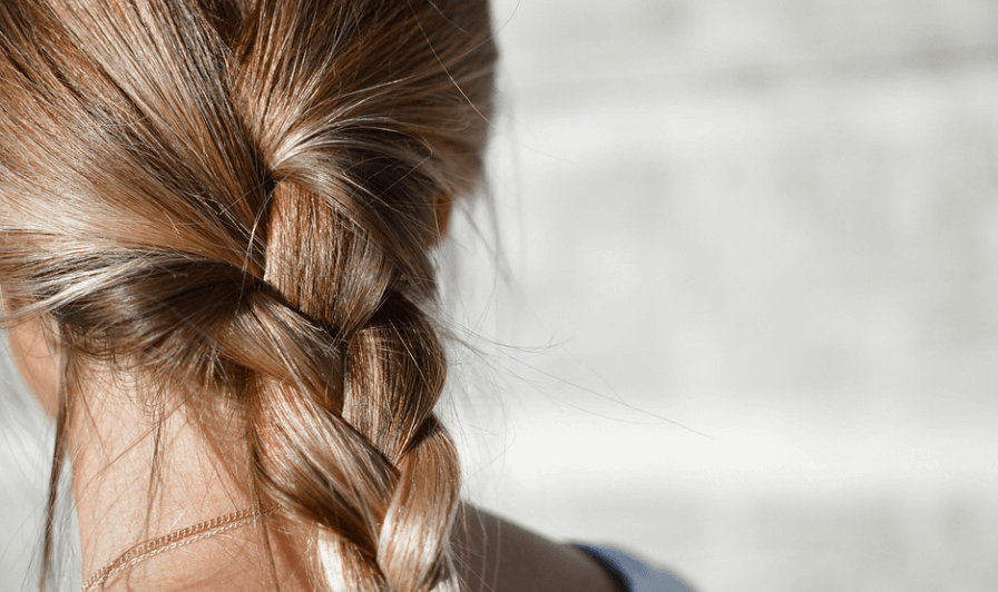 두피가 아픈 이유가 되는 묶음 머리를 하고 있는 여성