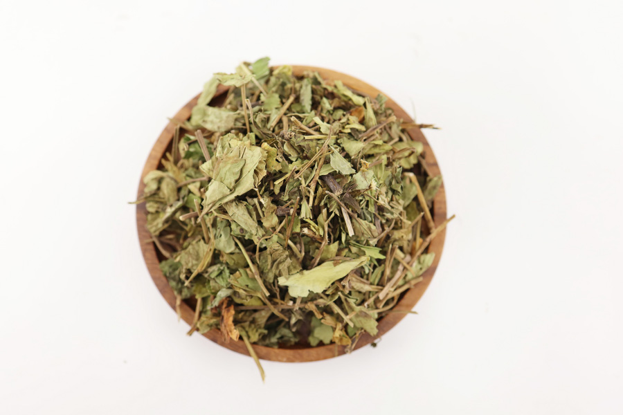 야생에서 채취를 한 삼백초 식물의 잎을 깨끗하게 세척을 한 후에 건조시킨 것을 하얀 바닥 위에 고동색의 동그란 나무 그릇에 가득 담아서 놓아두고 찍은 사진