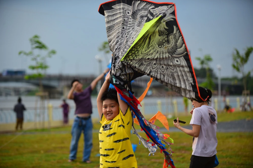 베트남의 학생들이 여름방학을 시작해 부모와 함께 연을 날리기위해 연을 손으로 높이 치켜 세워올리고있다