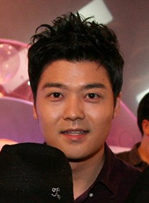 짧은 검은 머리의 남성이 웃으며 정면을 바라보는 얼굴 사진