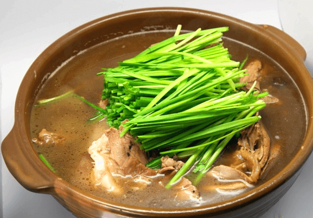 갈색 뚝배기에 오리백숙이 가득하다. 잘 익은 오리와 그 위에 녹색 부추가 가득하고, 국물도 많다.