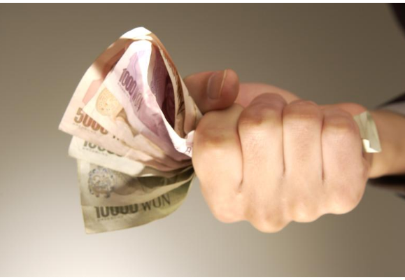 돈다발을 쥐고 있는 손의 모습.