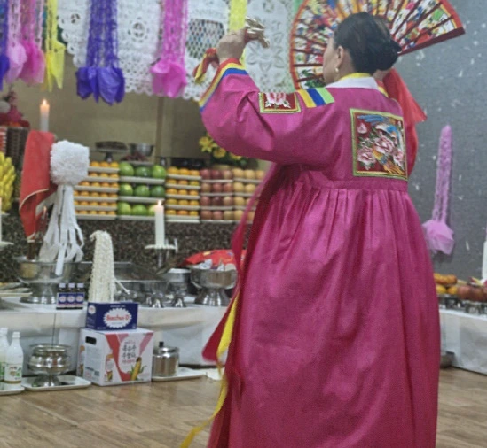 자주색 한복을 입고 굿 하는 모습