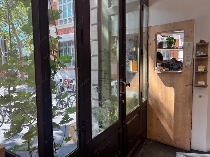 A view from inside The Broken Arm cafe looking out onto the sunny streets of Le Marais Paris ❘ Le cafe de The Broken Arm⁠
