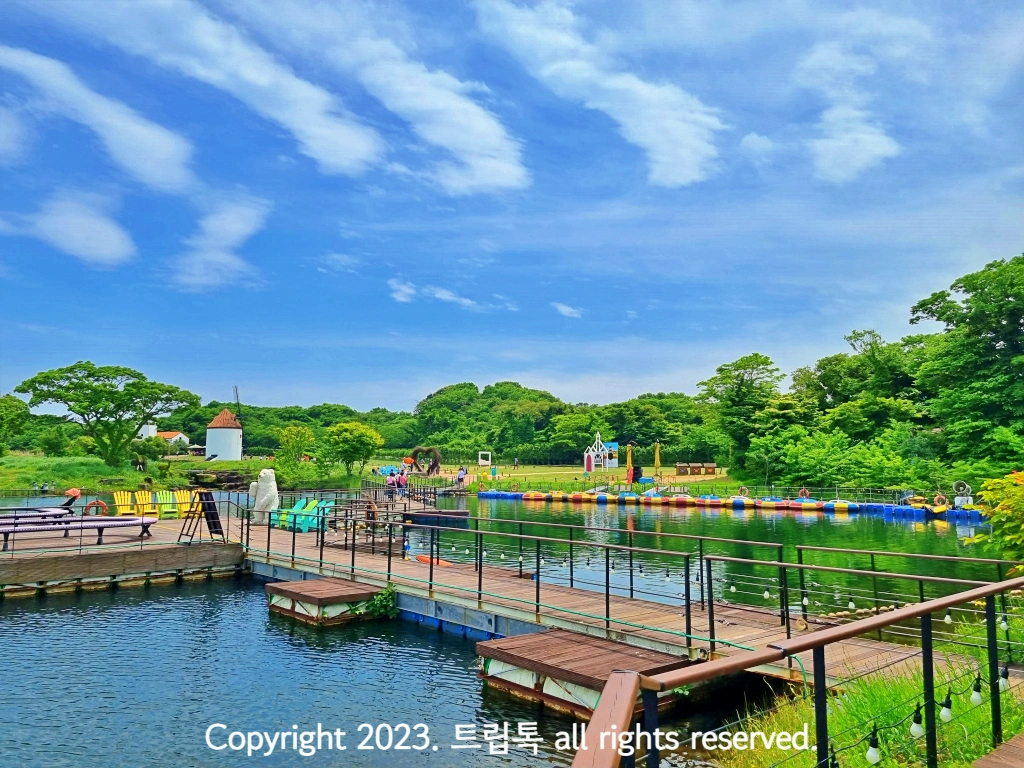 호수 옆에 푸른 숲과 데크로 이루어진 선착장이 있다