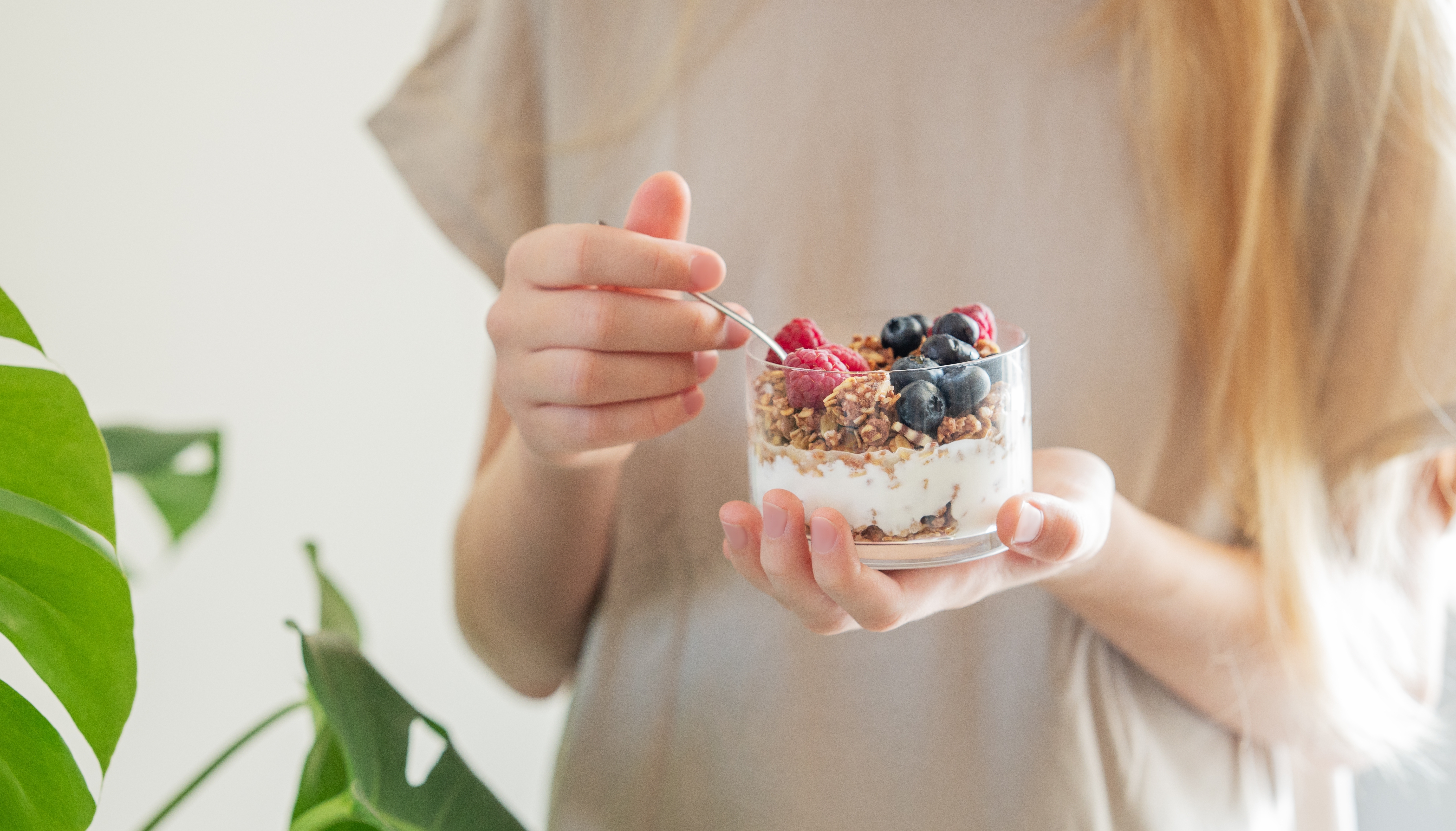 그릭요거트 위에 블루베리와 라즈베리를 올려 건강하게 먹는 여성의 손
