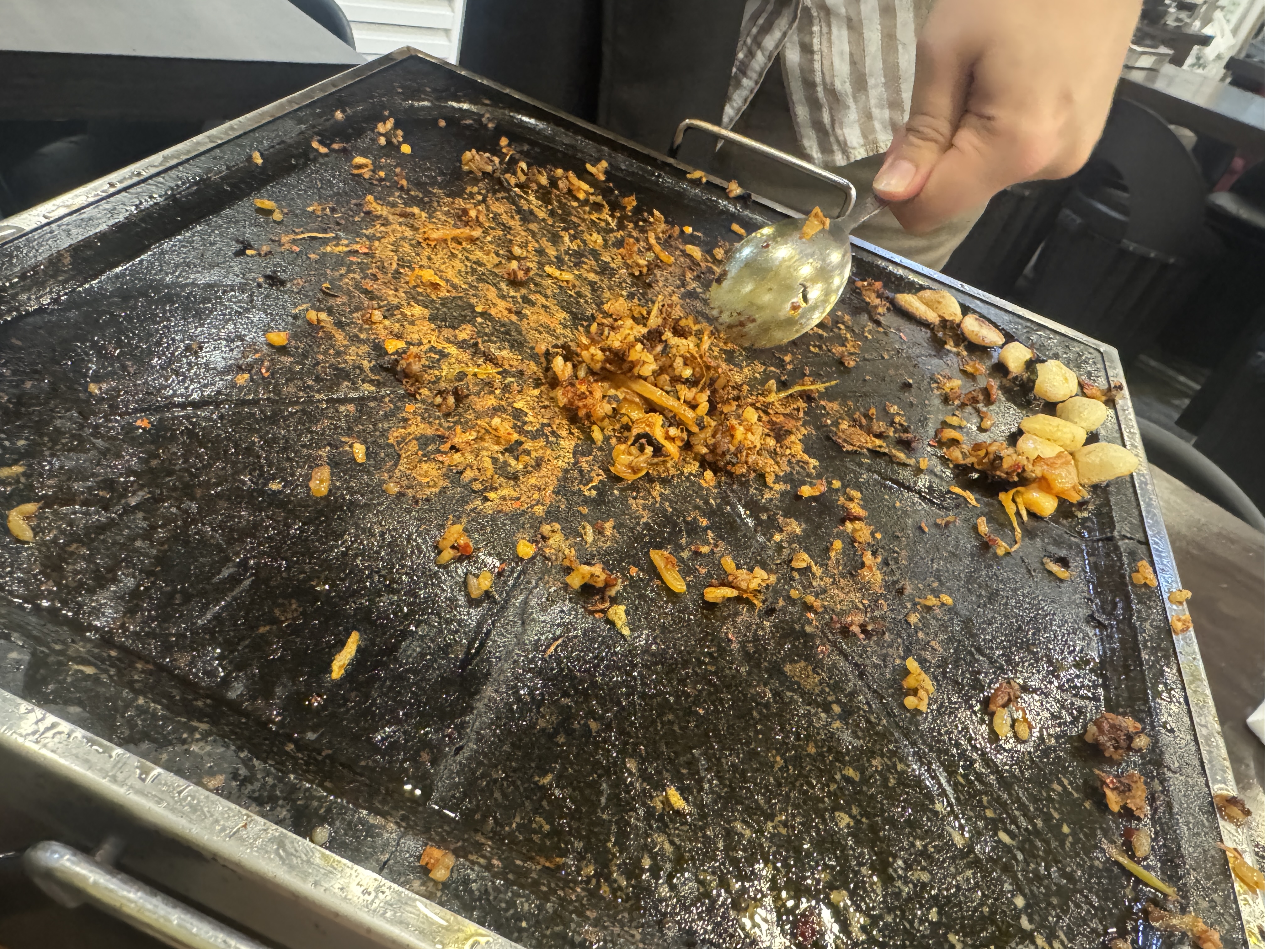 불판 위에 볶음밥 흔적만 남은 모습. 한쪽엔 마늘이 줄지어 구워져 있음.