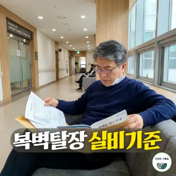 복벽탈장 실비기준. 50대 초반의 지적이고 차분한 인상을 가진 한국인 중년 남성이 대학병원 외과 진료실 앞 대기 복도 소파에 앉아, 복부 CT 검사 결과 판독지 서류 봉투와 실손보험 청구 안내문을 손에 든 채 집중하여 읽어 내려가고 있는 현실적이고 진지한 일상 모습.