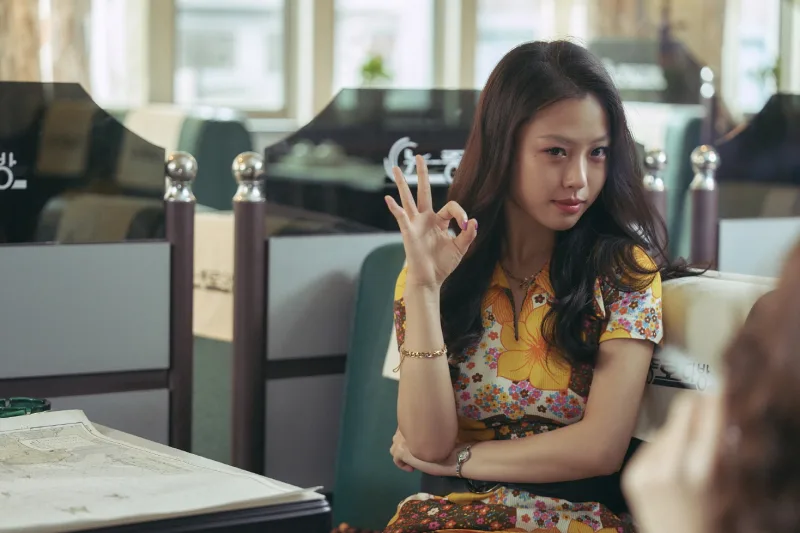 어느 다방을 배경으로 긴머리에 노랑 원피스를 입고 앉아 있는 영화 밀수의 배우 고민시