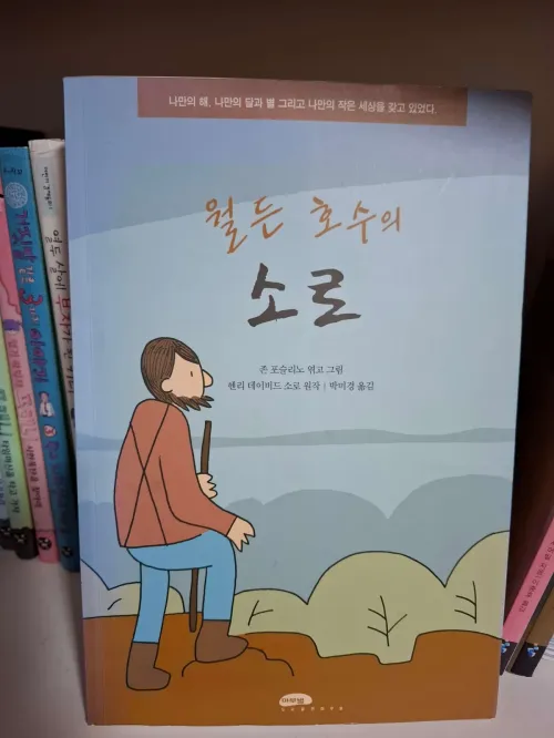 고요한 호숫가 옆 작은 통나무집 창가에서 낡은 수호수 인형을 곁에 두고 명상하며 세상의 소음으로부터 독립하려는 강인한 개인의 뒷모습(The back of a strong individual trying to become independent from the noise of the world while meditating with a small guardian doll by the window of a small log cabin by a quiet lake)