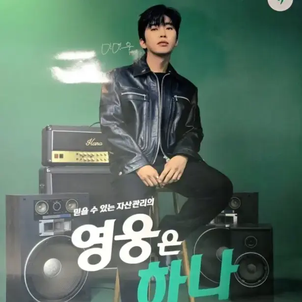 임영웅-
초록색 배경앞 각종 음악 기기 위에 검은 가죽쟈켓&#44; 검은 바지를 입고 앉아있는 임영웅