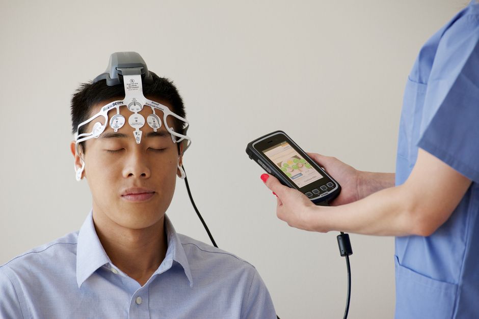 의료 전문가가 남성 환자에게 Brainscope 장치를 사용하여 EEG 검사를 실시하고 있습니다.