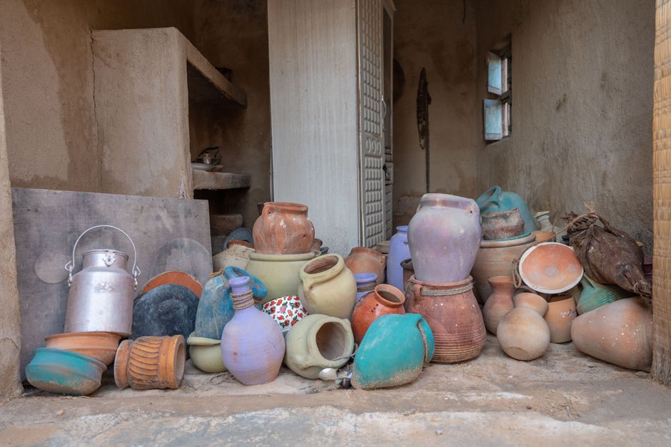 A diverse array of handmade clay pottery stacked in a rustic indoor setting.